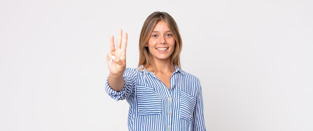 Photo jolie femme blonde souriante et semblant amicale, montrant le numéro quatre ou quatrième avec la main vers l'avant, compte à rebours