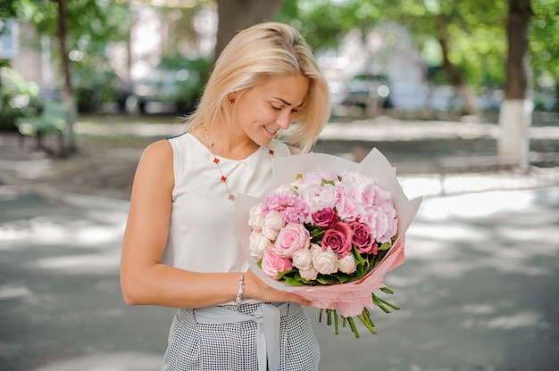 Jolie femme blonde tenant une belle composition de fleurs