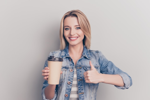 Jolie femme blonde tenant une tasse de café et donnant les pouces vers le haut