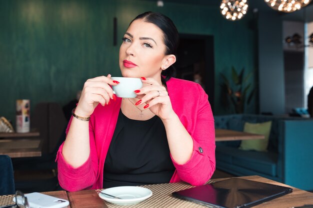 Jolie femme boit du café au café