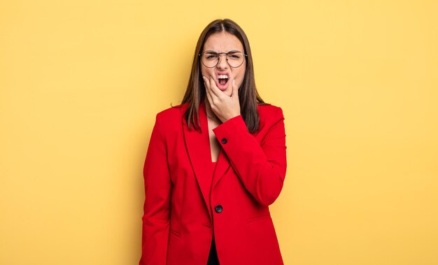 Jolie femme avec la bouche et les yeux grands ouverts et la main sur le concept de femme d'affaires de menton