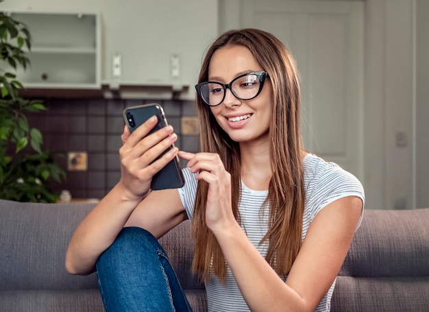 Jolie femme brune à l'aide de smartphone assis