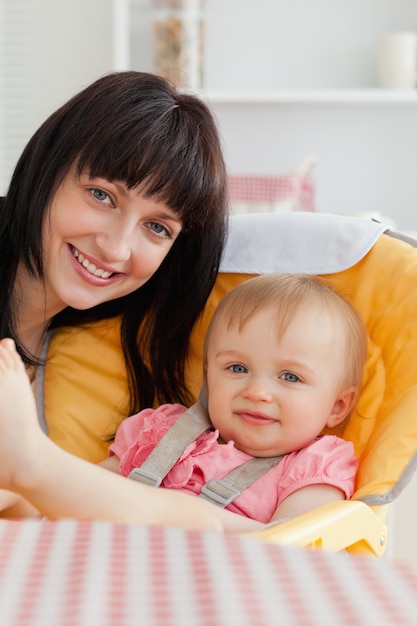 Jolie femme brune posant avec son bébé en position assise