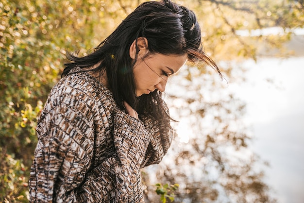 Jolie femme brune romantique posant contre le lac dans la montagne et la nature Concept de personnes et de style de vie Portrait d'une femme naturelle sensuelle porte un pull posant pendant le voyage Ambiance de fond