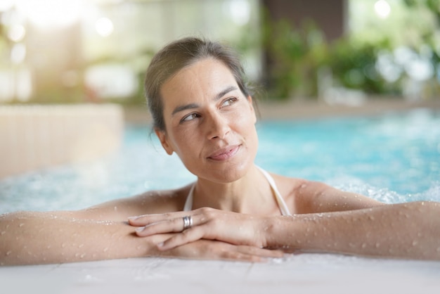 Jolie femme brune se détendre dans la piscine spa