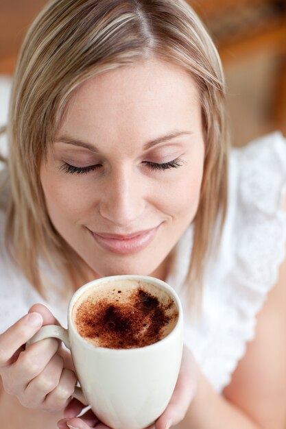 Jolie femme buvant un café assis sur un canapé