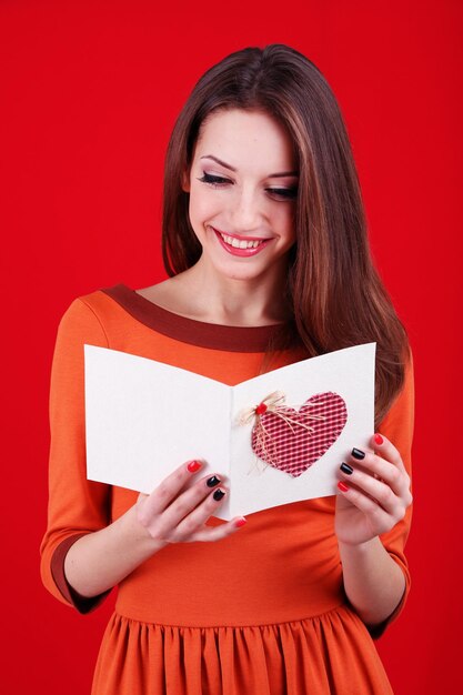 Jolie femme avec carte postale, sur fond rouge