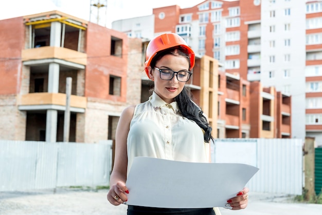 Jolie femme en casque de constructeur en regardant le plan