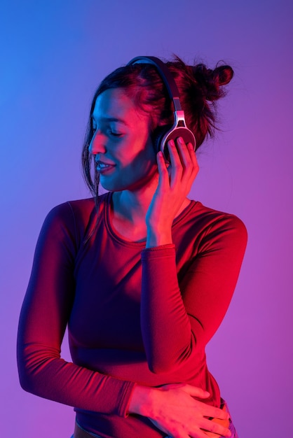 Jolie femme avec un casque d'écoute de la musique en studio avec des lumières bleues et rouges