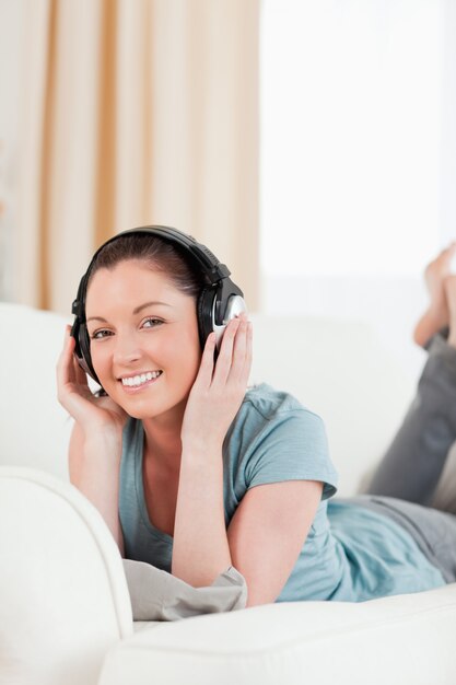 Jolie femme avec un casque posant en position couchée sur un canapé