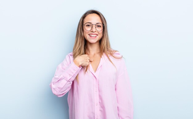 Jolie femme caucasienne à l'air heureuse, fière et surprise, se montrant joyeusement elle-même, se sentant confiante et élevée