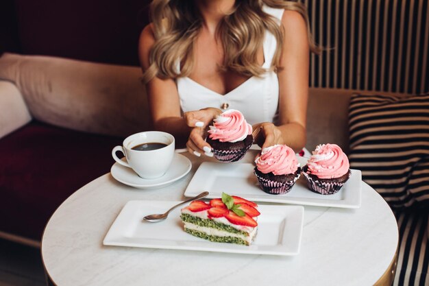 Photo une jolie femme caucasienne aux longs cheveux blonds ondulés est assise sur le canapé à boire du café.