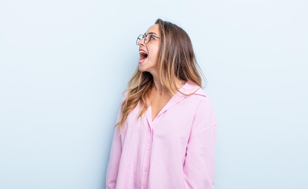 Jolie femme caucasienne criant furieusement, criant agressivement, l'air stressée et en colère