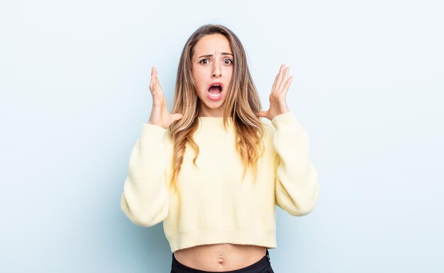 Jolie femme caucasienne criant avec les mains en l'air, se sentant furieuse, frustrée, stressée et contrariée