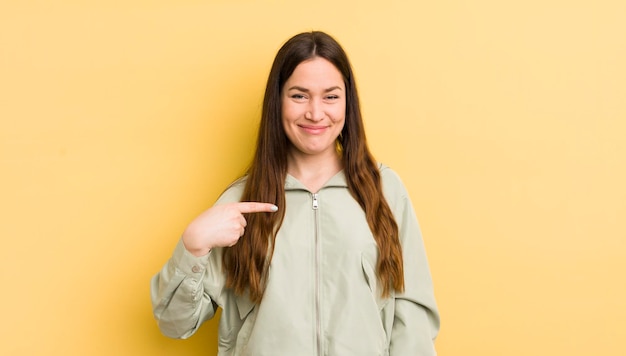 Jolie femme caucasienne à la fierté confiante et heureuse souriante et pointant vers soi ou faisant le signe numéro un