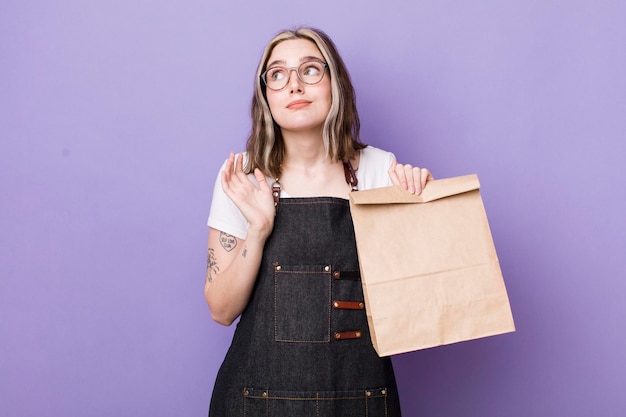 Jolie femme caucasienne haussant les épaules se sentant confuse et incertaine livraison et concept à emporter