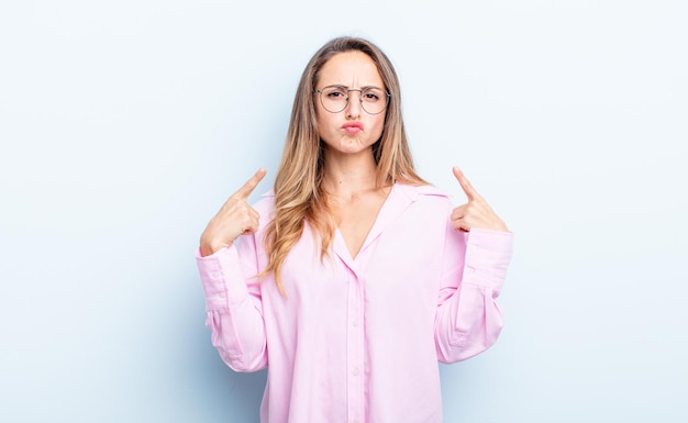 Jolie femme caucasienne avec une mauvaise attitude semblant fière et agressive, pointant vers le haut ou faisant un signe amusant avec les mains