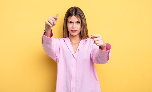 Jolie femme caucasienne pointant vers l'avant à la caméra avec les deux doigts et une expression de colère, vous disant de faire votre devoir