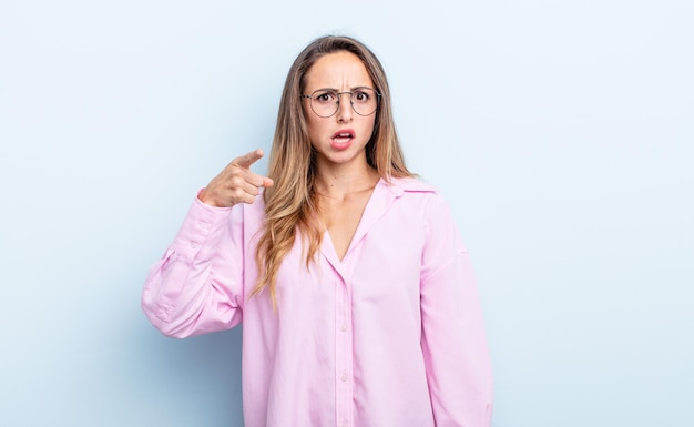 Jolie femme caucasienne pointant vers la caméra avec une expression agressive en colère ressemblant à un patron furieux et fou