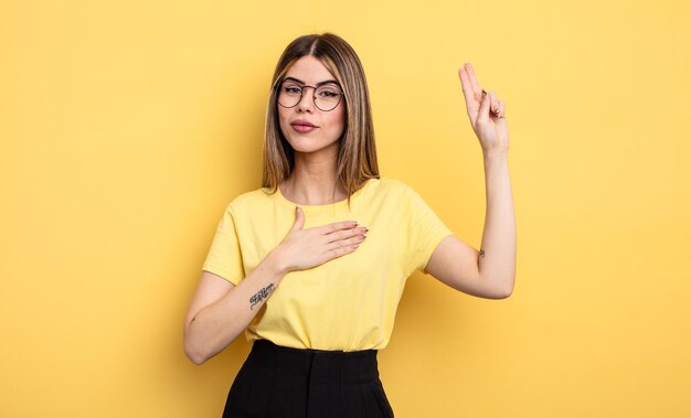 Jolie femme caucasienne qui a l'air heureuse, confiante et digne de confiance, souriante et montrant le signe de la victoire avec une attitude positive