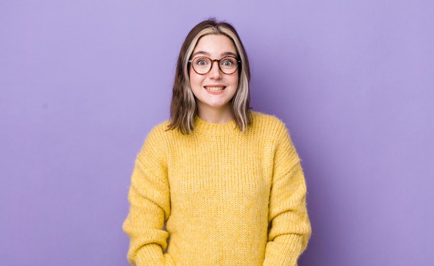 Jolie femme caucasienne qui a l'air heureuse et maladroite avec un large sourire amusant et des yeux grands ouverts