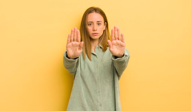 Jolie femme caucasienne à la recherche de graves mécontents en colère et mécontents interdisant l'entrée ou disant d'arrêter avec les deux paumes ouvertes