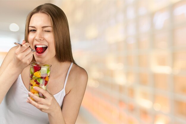 Jolie femme caucasienne avec salade de fruits sur fond