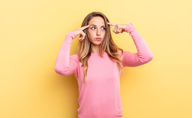 Jolie femme caucasienne se sentant confuse ou doutant, se concentrant sur une idée, réfléchissant fort, cherchant à copier l'espace sur le côté