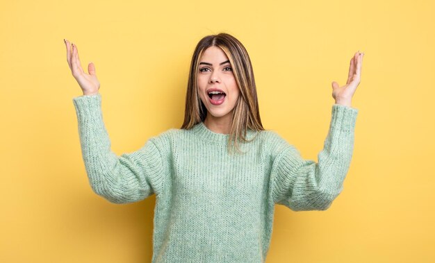 Jolie femme caucasienne se sentant heureuse, étonnée, chanceuse et surprise, célébrant la victoire avec les deux mains en l'air