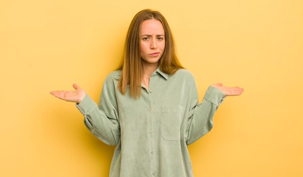 Jolie femme caucasienne se sentant perplexe et confuse doutant de la pondération ou choisissant différentes options avec une drôle d'expression