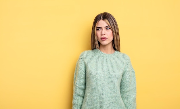 Jolie femme caucasienne se sentant triste, bouleversée ou en colère et regardant de côté avec une attitude négative, fronçant les sourcils en désaccord