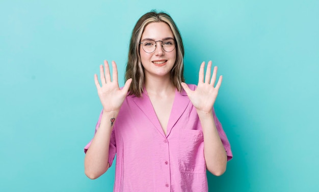 Jolie femme caucasienne souriante et amicale montrant le numéro dix ou dixième avec la main en avant compte à rebours