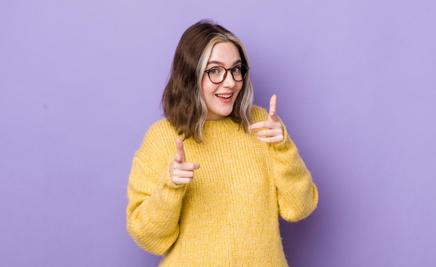 Jolie femme caucasienne souriante avec une attitude heureuse réussie positive pointant vers la caméra faisant signe de pistolet avec les mains