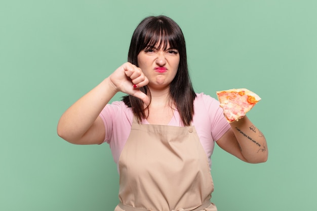 Jolie femme chef expression en colère et tenant une pizza