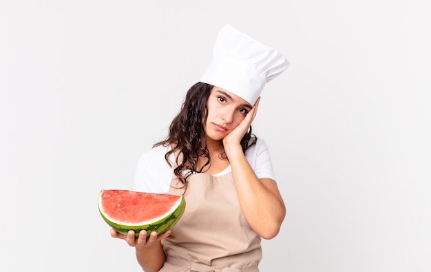 Jolie femme chef hispanique se sentant ennuyée, frustrée et somnolente après un fastidieux et tenant une pastèque