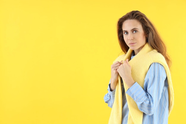 Jolie femme en chemise avec pull sur fond jaune