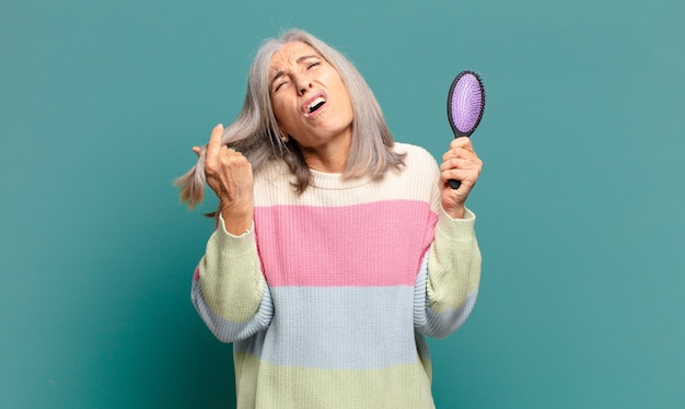 Jolie femme cheveux gris avec une brosse à cheveux