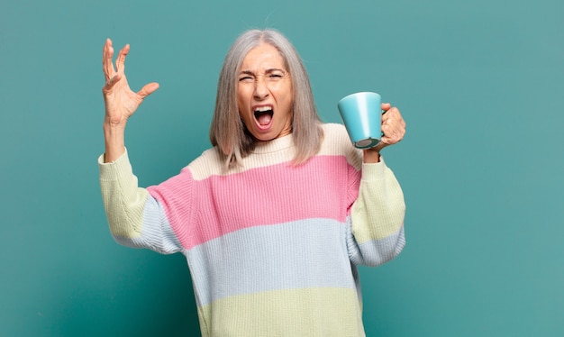 Jolie femme cheveux gris avec un café ou un thé