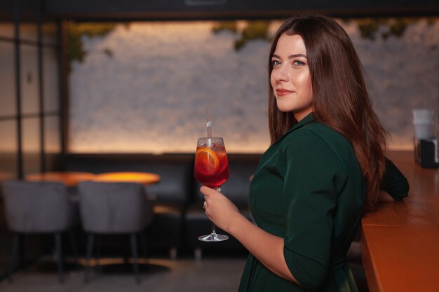 Jolie femme chic prenant un verre au bar le soir