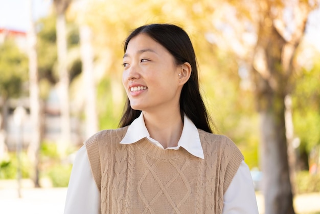 Jolie femme chinoise à l'extérieur avec une expression heureuse