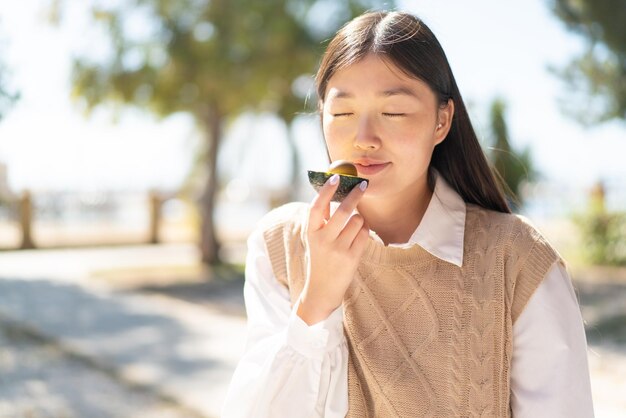 Jolie femme chinoise à l'extérieur tenant un avocat