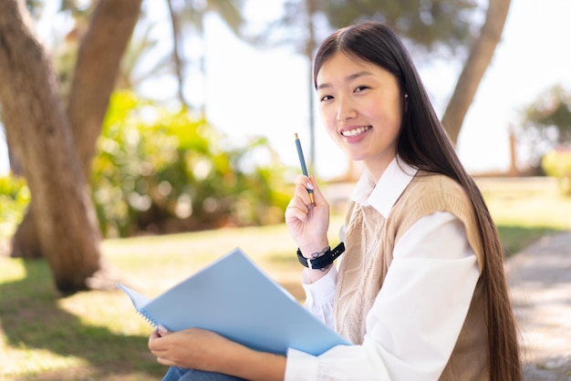 Jolie femme chinoise à l'extérieur tenant un carnet