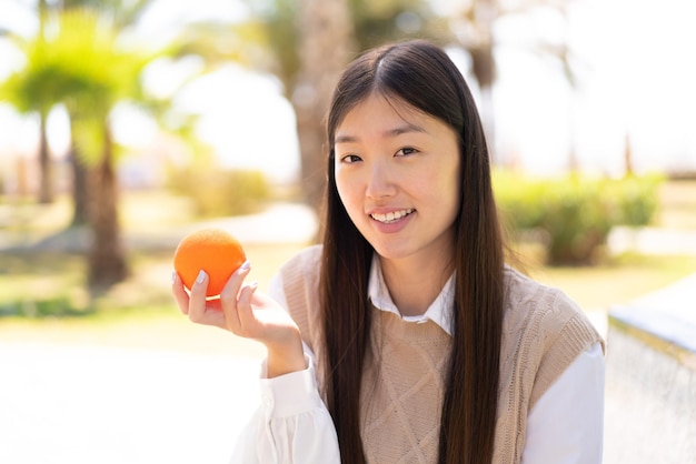 Jolie femme chinoise à l'extérieur tenant une orange