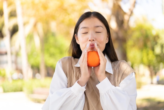 Jolie femme chinoise à l'extérieur tenant une orange