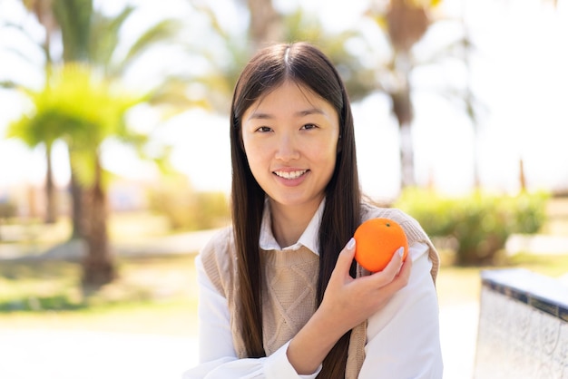 Jolie femme chinoise à l'extérieur tenant une orange