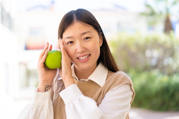 Jolie femme chinoise à l'extérieur tenant une pomme