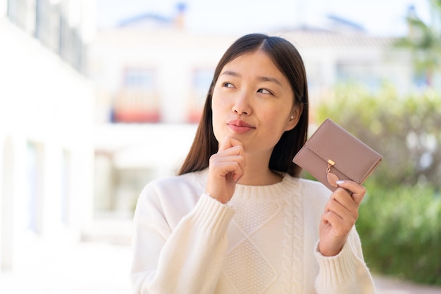 Jolie femme chinoise à l'extérieur tenant un portefeuille