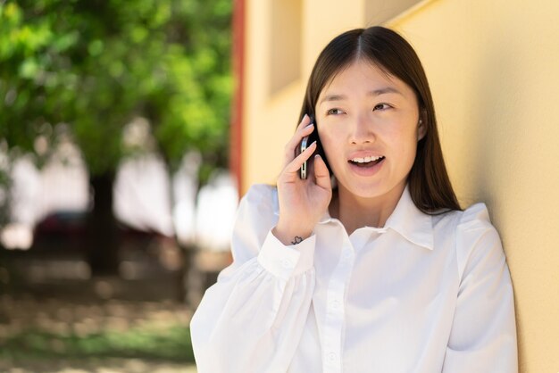 Jolie femme chinoise utilisant un téléphone portable à l'extérieur