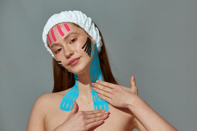 Jolie femme collant des bandes de ruban adhésif de levage du visage sur le cou pour resserrer les rides de lissage de la peau