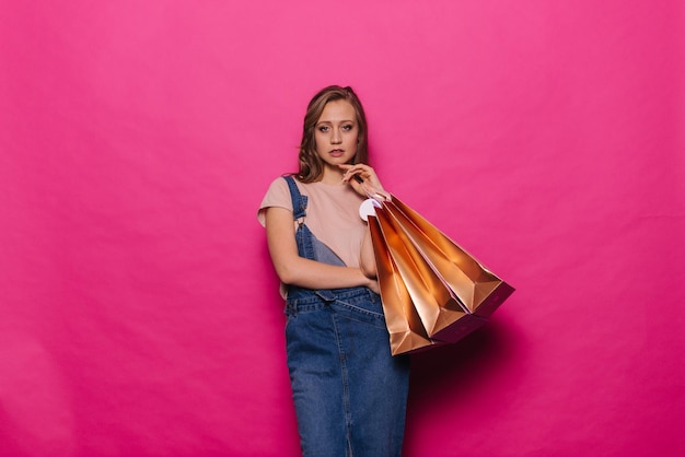 Jolie femme commerçante posant avec des sacs à provisions colorés sur fond rose